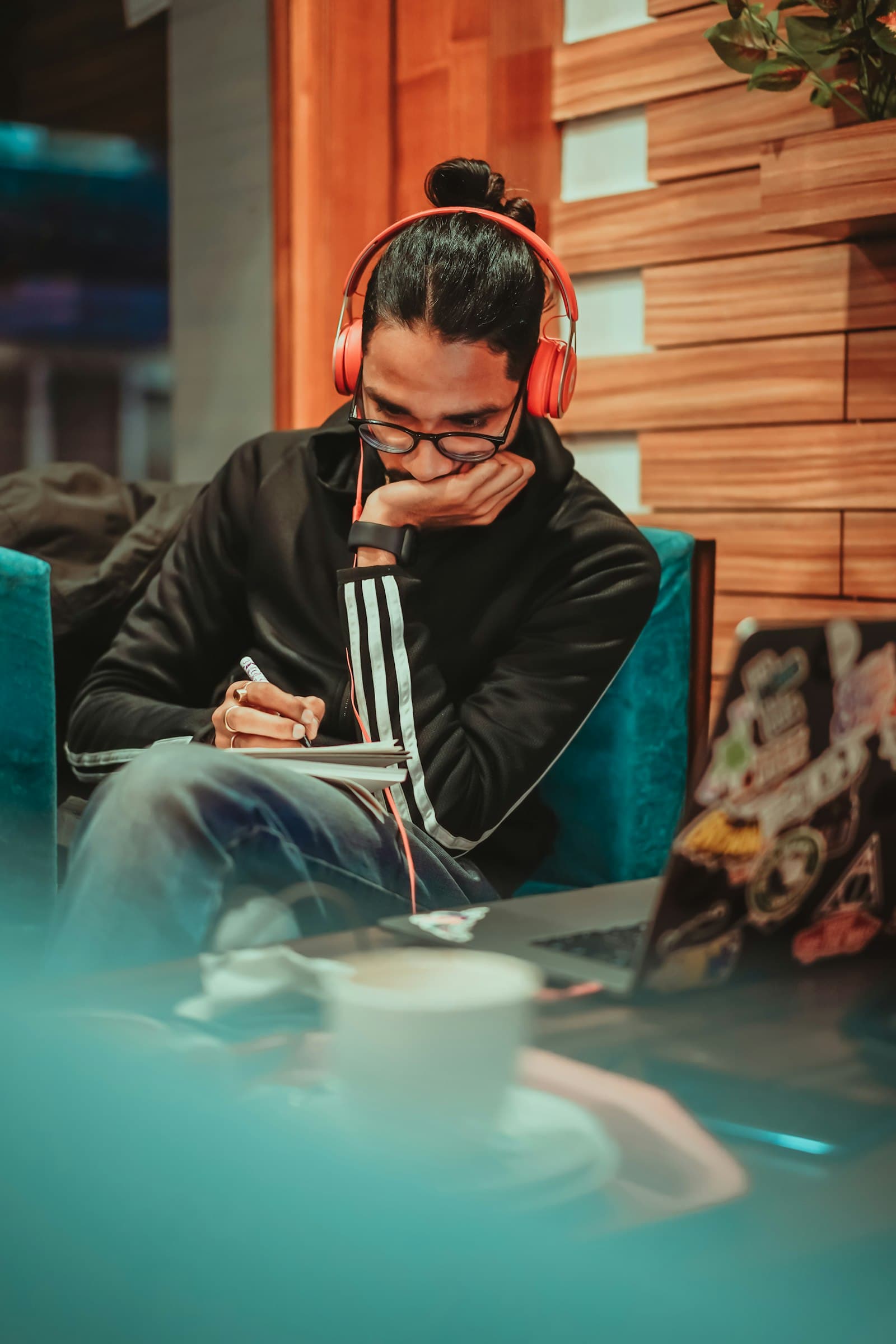 A student in headphones writing notes while studying